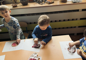 Zdjęcie przedstawia dzieci które wykonują papierowego pączka