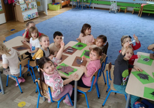 Dzieci siedzące przy stolikach, malujące widelcem