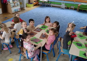 Dzieci siedzące przy stolikach, malujące widelcem