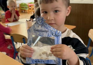 Zdjęcie przedstawia dziecko z domkiem dla fasolek