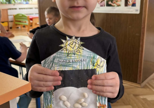 Zdjęcie przedstawia dziecko z domkiem dla fasolek