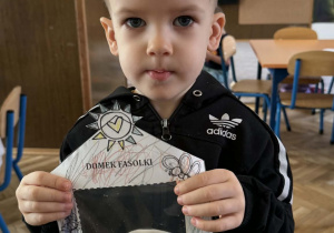 Zdjęcie przedstawia dziecko z domkiem dla fasolek