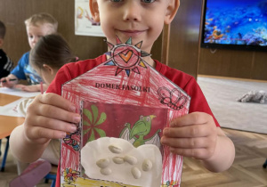 Zdjęcie przedstawia dziecko z domkiem dla fasolek