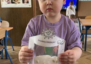 Zdjęcie przedstawia dziecko z domkiem dla fasolek