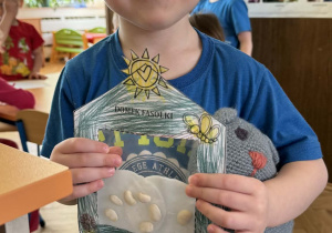 Zdjęcie przedstawia dziecko z domkiem dla fasolek