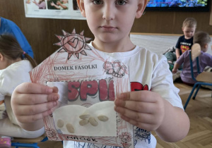 Zdjęcie przedstawia dziecko z domkiem dla fasolek