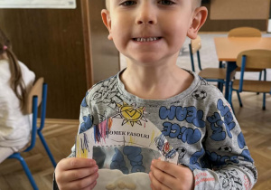 Zdjęcie przedstawia dziecko z domkiem dla fasolek