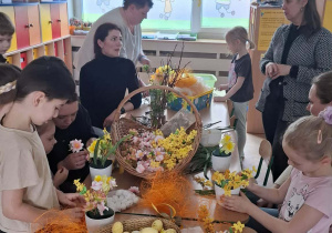 Dzieci i rodzice podczas wspólnego tworzenia stroików wielkanocnych