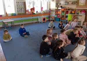 Dzieci siedzące na dywanie podczas zajęć