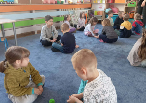 Dzieci siedzące na dywanie w parach podczas zajęć