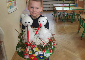 Chłopiec trzyma swoją pracę -kapelusz z dwoma bocianami