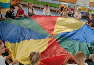 dzieci siedzące w okręgu wykonują ćwiczenia związane z kropką
