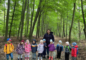 Zdjęcie przedstawia grupę dzieci w lesie