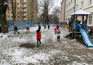 Zdjęcie przedstawia dzieci w ogrodzie przedszkolnym w zimową pogodę