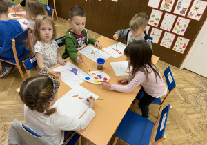 zdjęcie przedstawia dzieci, które malują i ozdabiają rysunek bombki