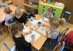zdjęcie przedstawia dzieci, które malują i ozdabiają rysunek bombki