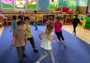 Zdjęcie przedstawia dzieci w trakcie zajęć ruchowych