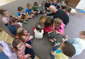 Zdjęcie przedstawia dzieci w trakcie warsztatów szachowych