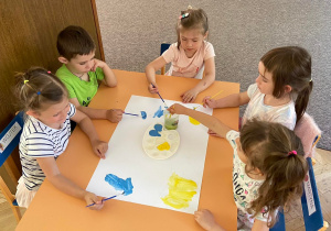 Zdjęcie przedstawia dzieci tworzące plakat wakacje nad morzem