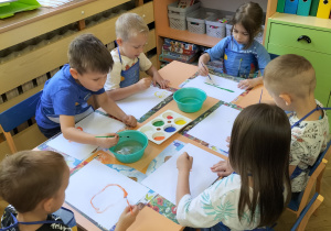 Zdjęcie przedstawia dzieci w trakcie malowania farbami