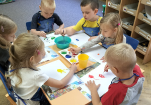 Zdjęcie przedstawia dzieci w trakcie malowania farbami