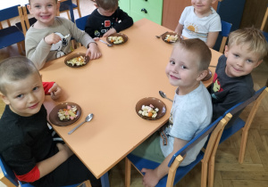 Zdjęcie przedstawia dzieci w trakcie jedzenia sałatki owocowej