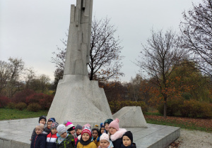 Zdjęcie przedstawia dzieci pod pomnikiem żołnierzy
