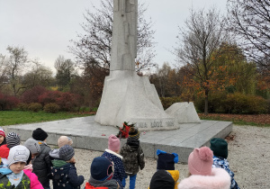 Zdjęcie przedstawia dzieci pod pomnikiem żołnierzy