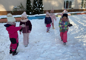 Zdjęcie przedstawia dzieci w trakcie zabaw na śniegu