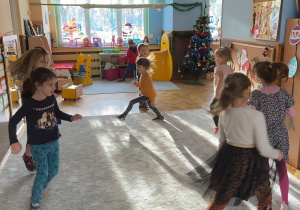 Zdjęcie przedstawia dzieci tańczące na dywanie