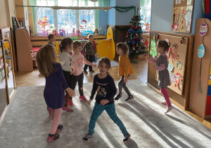 Zdjęcie przedstawia dzieci tańczące na dywanie